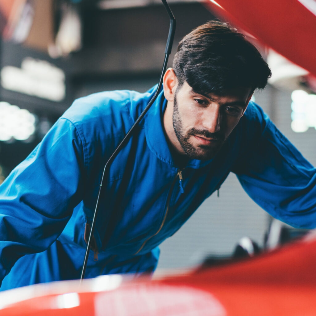 Auto mechanic young man checking and repairing car radiator bonnet in automotive condition in garage at auto repair shop, motor technician working after vehicle service maintenance concept